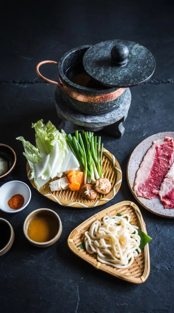 Sukiyaki: panela de pedra com caldo quente, wagyu fatiado, cogumelos, legumes e udon